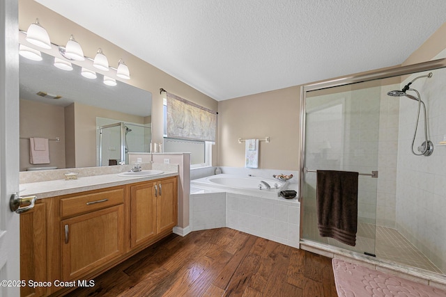 bathroom featuring vanity, hardwood / wood-style flooring, plus walk in shower, and a textured ceiling