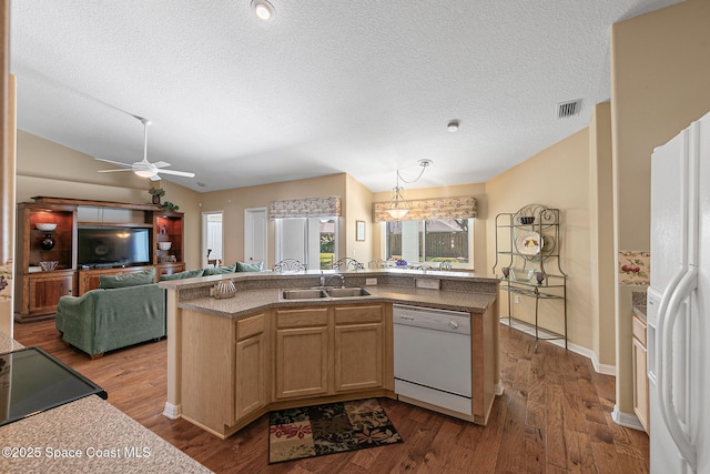 kitchen with sink, vaulted ceiling, a textured ceiling, white appliances, and light hardwood / wood-style floors