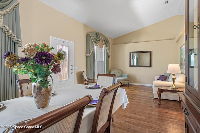 dining room featuring lofted ceiling and dark hardwood / wood-style flooring