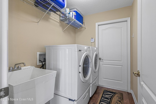 clothes washing area with dark hardwood / wood-style flooring, sink, washer and dryer, and a textured ceiling