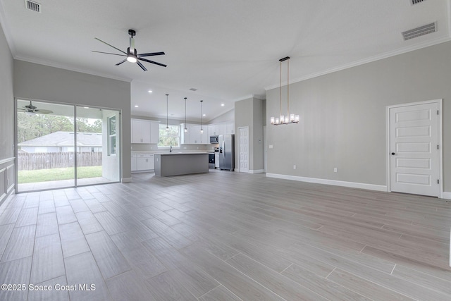 unfurnished living room featuring crown molding, lofted ceiling, sink, and ceiling fan with notable chandelier