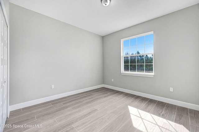 spare room featuring light wood-type flooring and baseboards