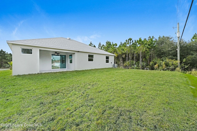 back of house with a lawn and stucco siding