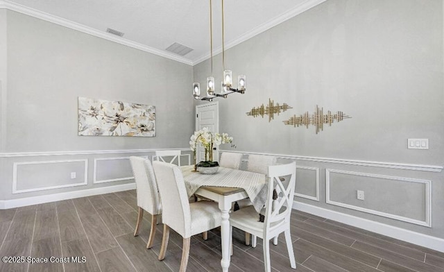 dining area featuring a chandelier, ornamental molding, visible vents, and wood tiled floor