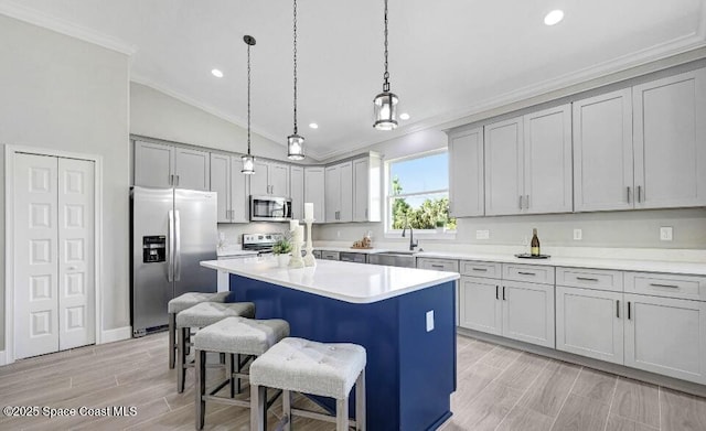 kitchen featuring a breakfast bar, a center island, crown molding, stainless steel appliances, and a sink