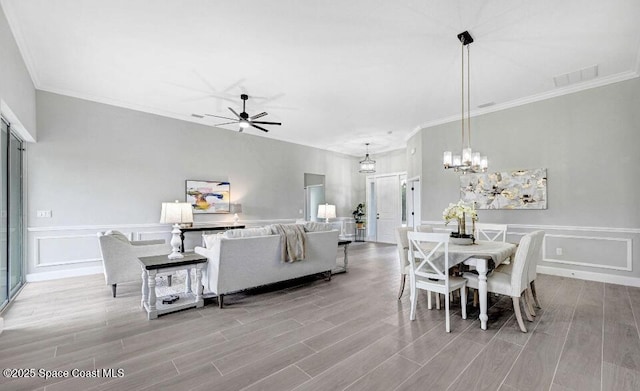 dining room with light wood-style floors, visible vents, a decorative wall, and ceiling fan with notable chandelier