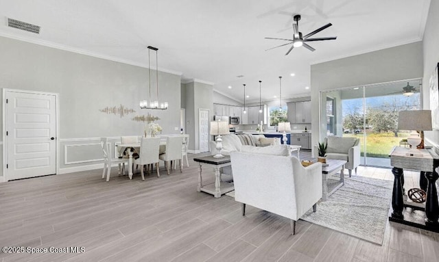 living room featuring light wood-type flooring, visible vents, crown molding, and ceiling fan with notable chandelier