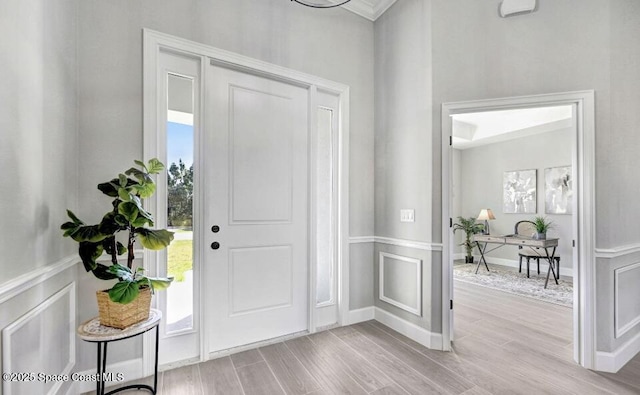 entryway featuring a wainscoted wall, a decorative wall, and wood finished floors