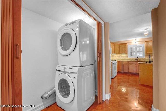 laundry area featuring stacked washer and dryer, sink, and a textured ceiling