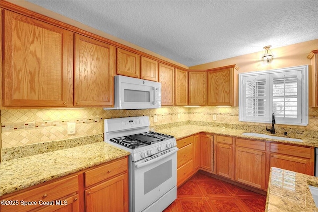 kitchen featuring sink, tasteful backsplash, a textured ceiling, white appliances, and light stone countertops