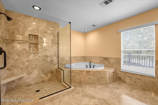 bathroom with independent shower and bath, plenty of natural light, and a textured ceiling