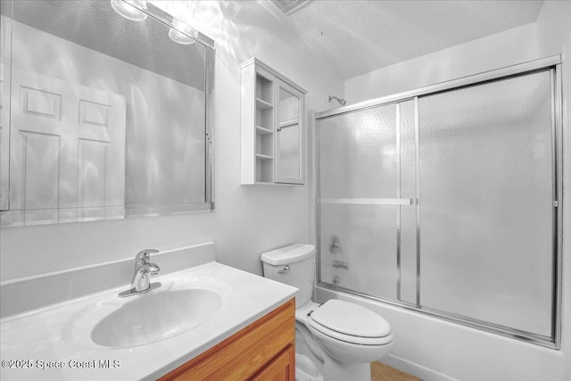 full bathroom with bath / shower combo with glass door, vanity, a textured ceiling, and toilet