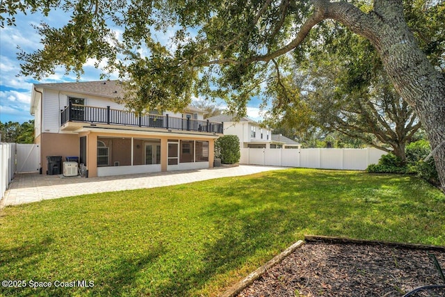 back of property featuring a lawn, a sunroom, and a patio