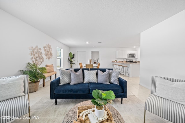 living area with light tile patterned floors, a textured ceiling, and baseboards