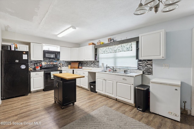 225 Court St, Titusville, FL 32780 - kitchen with black appliances, butcher block counters, tasteful backsplash, white cabinets, and a textured ceiling