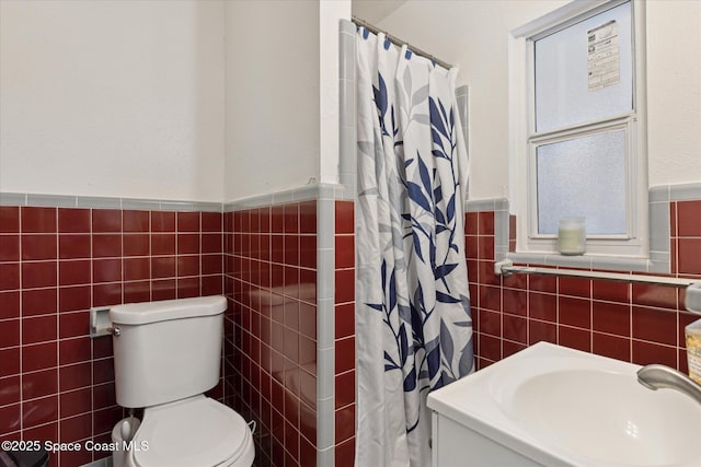 225 Court St, Titusville, FL 32780 - bathroom with tile walls, wainscoting, toilet, curtained shower, and a sink
