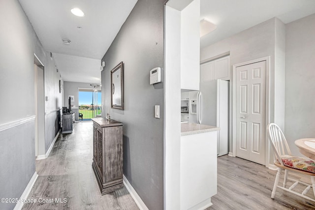 hall featuring light wood-type flooring and baseboards