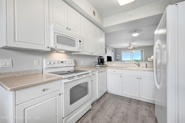 kitchen featuring light countertops, white appliances, a sink, and white cabinets