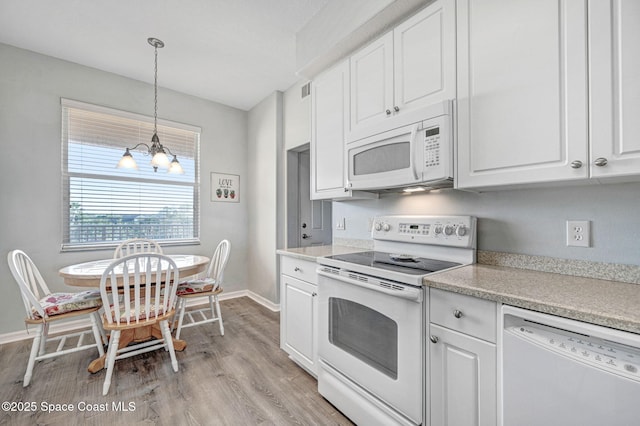 kitchen with pendant lighting, white appliances, light countertops, and white cabinets