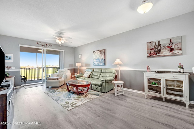 living area with light wood finished floors, baseboards, and a ceiling fan