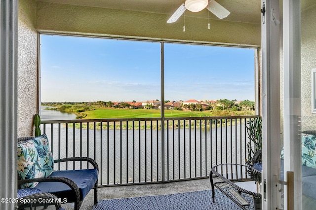 sunroom with ceiling fan and a water view