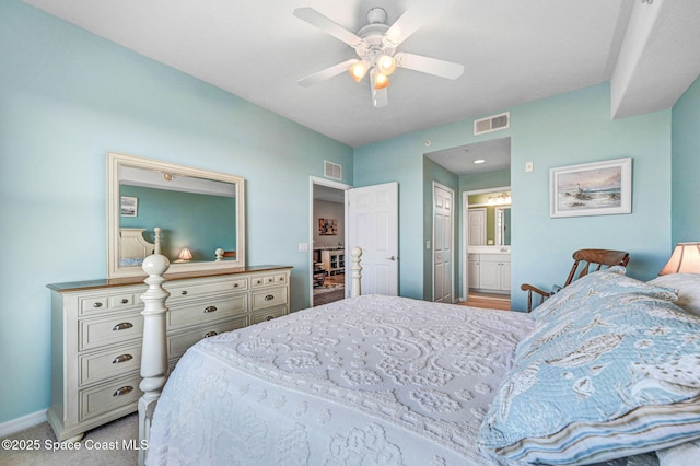 bedroom featuring visible vents, ceiling fan, light carpet, and ensuite bath