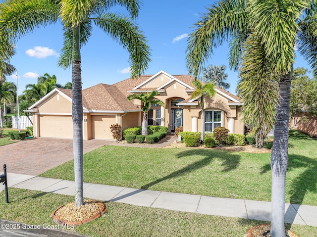 view of front of home featuring a garage, decorative driveway, a front lawn, and stucco siding