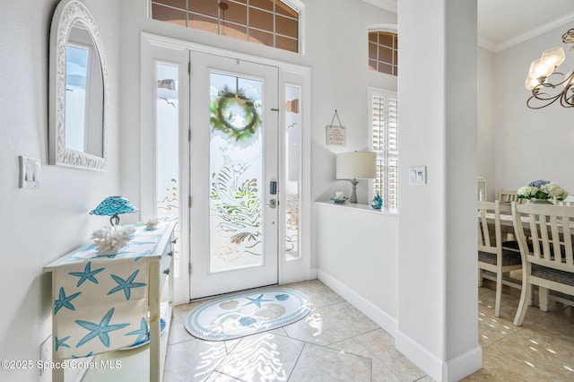 entrance foyer with a chandelier, light tile patterned floors, baseboards, and crown molding