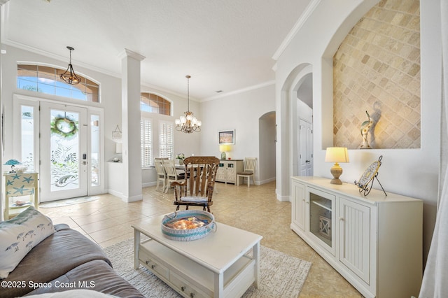 living area featuring light tile patterned floors, baseboards, arched walkways, ornamental molding, and a chandelier