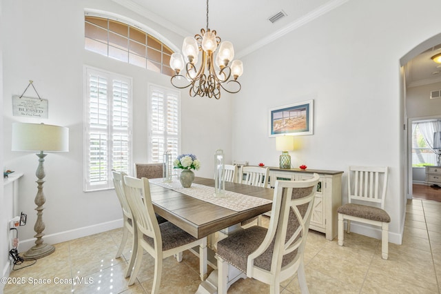 dining room featuring ornamental molding, arched walkways, visible vents, and baseboards