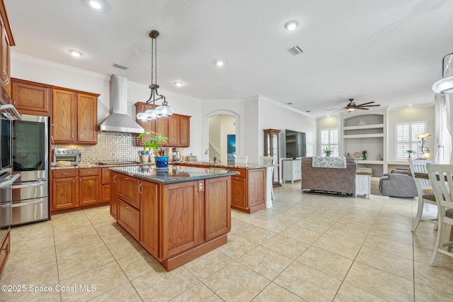 kitchen featuring pendant lighting, visible vents, open floor plan, a kitchen island, and wall chimney range hood