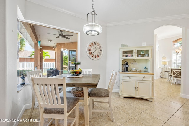 dining area featuring arched walkways, light tile patterned floors, a ceiling fan, baseboards, and crown molding