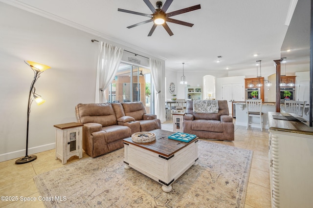 living area featuring crown molding, baseboards, a ceiling fan, and light tile patterned flooring