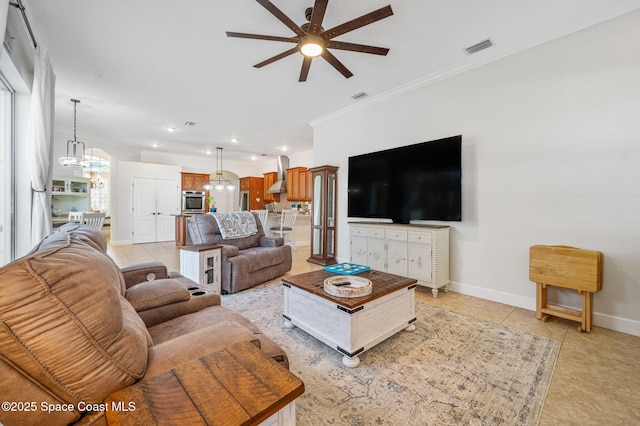 living area with light tile patterned floors, ornamental molding, visible vents, and baseboards