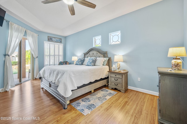 bedroom with ceiling fan, baseboards, light wood-style floors, access to outside, and a raised ceiling