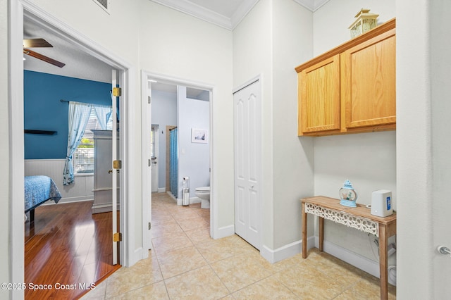 hallway with light tile patterned floors, baseboards, and crown molding