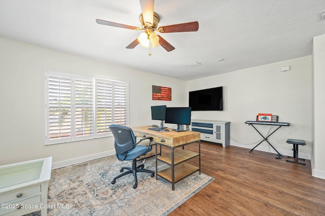 office space with visible vents, a ceiling fan, a textured ceiling, wood finished floors, and baseboards