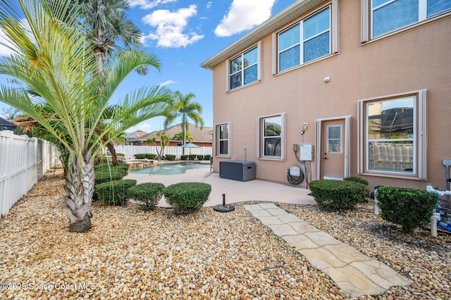 rear view of house with a fenced in pool, a fenced backyard, a patio, and stucco siding