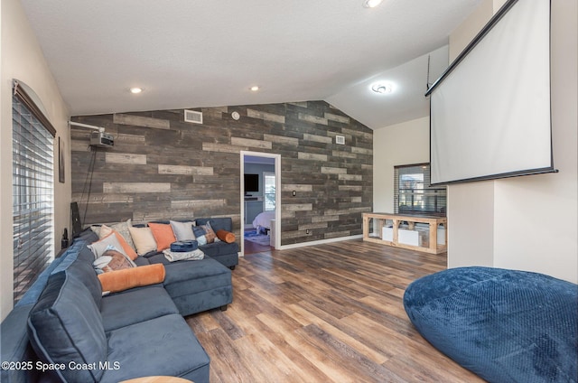 living room with hardwood / wood-style flooring, wooden walls, vaulted ceiling, and a textured ceiling