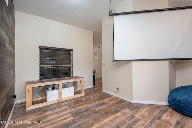 home theater with lofted ceiling, hardwood / wood-style floors, and a textured ceiling