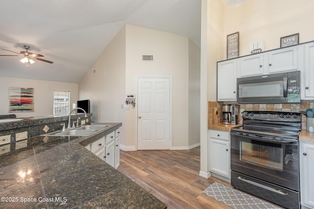 kitchen with sink, white cabinets, backsplash, black appliances, and light hardwood / wood-style flooring