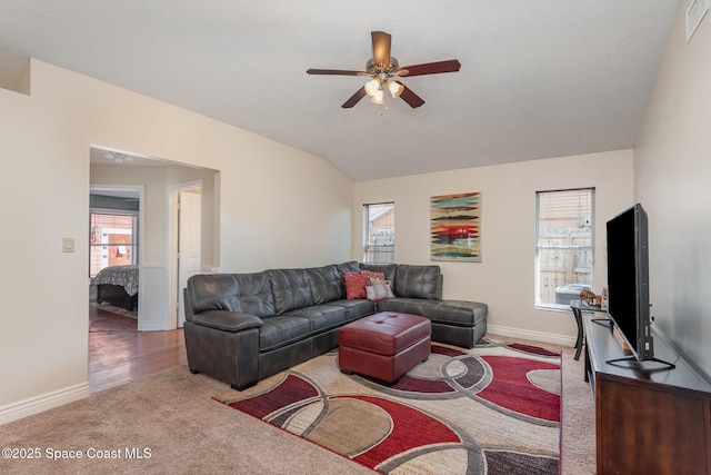 living room featuring light carpet, a textured ceiling, vaulted ceiling, and ceiling fan