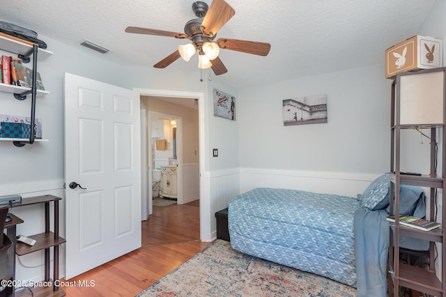 bedroom featuring ceiling fan, wood-type flooring, and a textured ceiling