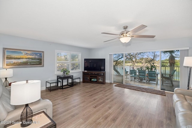 living area with a wealth of natural light, baseboards, and wood finished floors