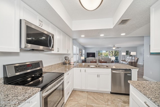 kitchen with a peninsula, a sink, visible vents, open floor plan, and appliances with stainless steel finishes