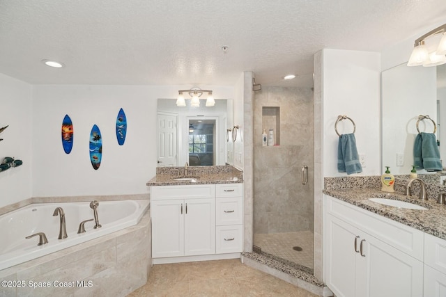 bathroom with a garden tub, a stall shower, a sink, a textured ceiling, and tile patterned floors