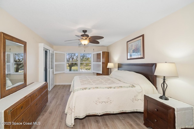 bedroom with a ceiling fan, light wood-style flooring, and baseboards