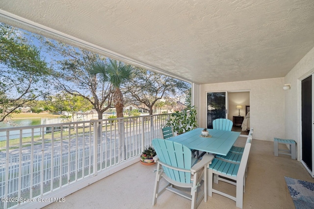 balcony featuring a water view and outdoor dining area