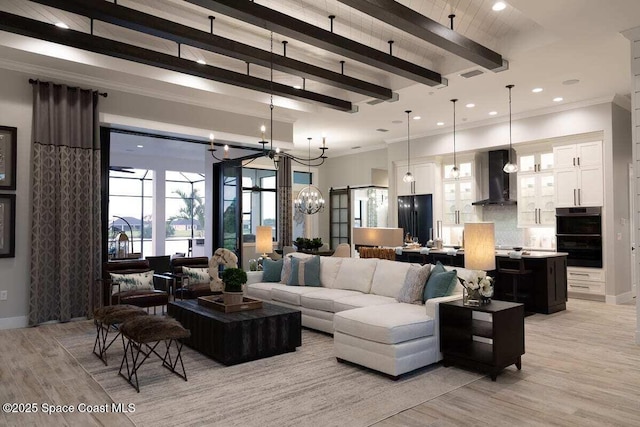 living room with beamed ceiling, ornamental molding, a barn door, and light hardwood / wood-style floors