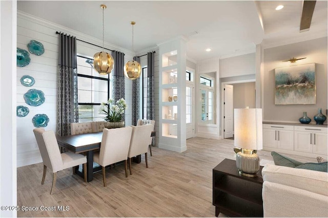 dining room with crown molding, an inviting chandelier, and light wood-type flooring